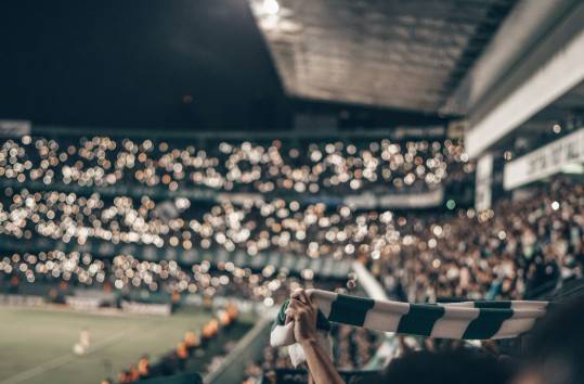 From stadium chants to viral hits: how football influences music Football stadium with a green and white striped shirt held up in the foreground